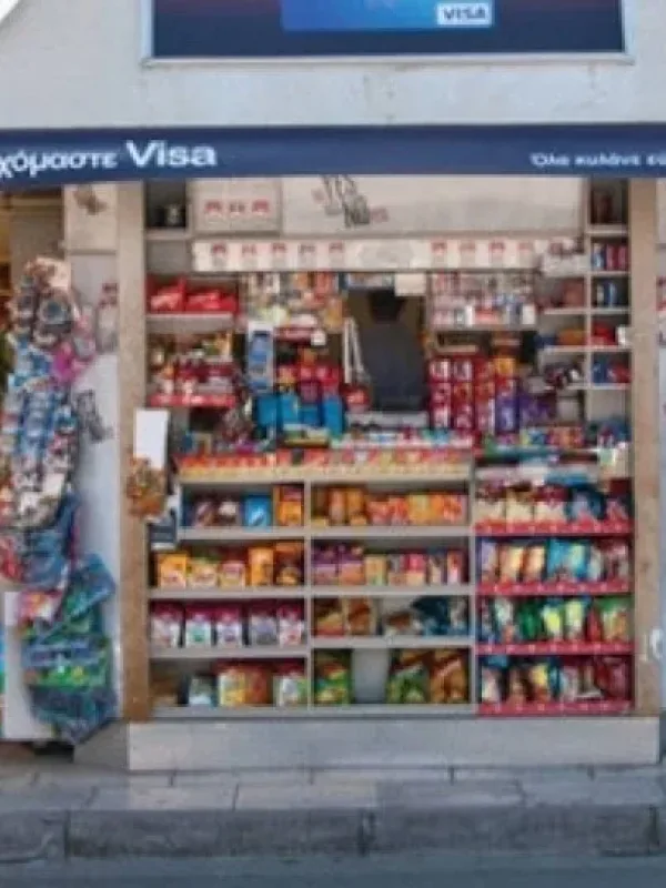 Παραδοσιακα ελληνικά περίπτερα σε αστική γωνία, με προϊόντα και περιοδικά, σε φόντο σύγχρονης πόλης.